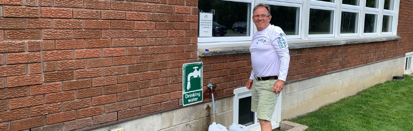 Resident filling water containers at the public drinking water station at the Townhall
